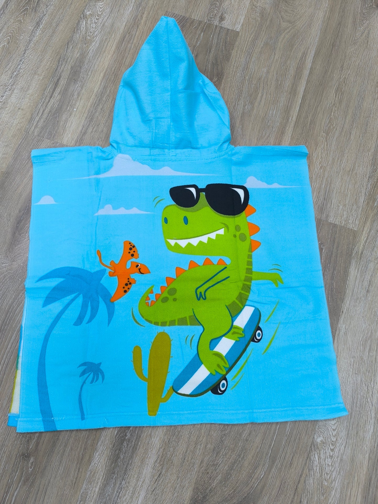 Toalla poncho con gorro para niño – Dinosaurio skater azul | Ligera, divertida y de secado rápido (60x120 cm)