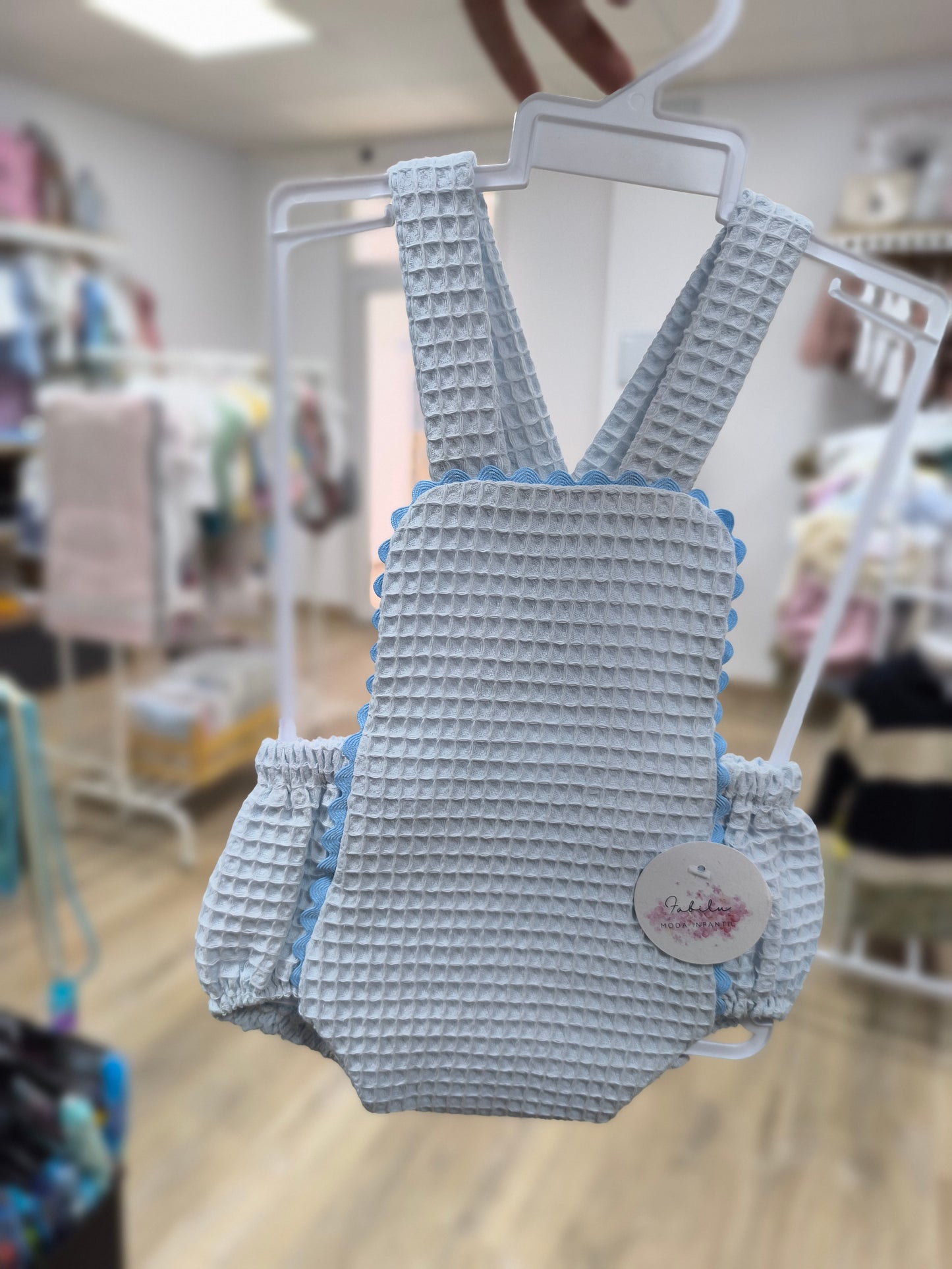 Ranita de bebé unisex en color celeste de tejido waffle con tirantes y puntilla